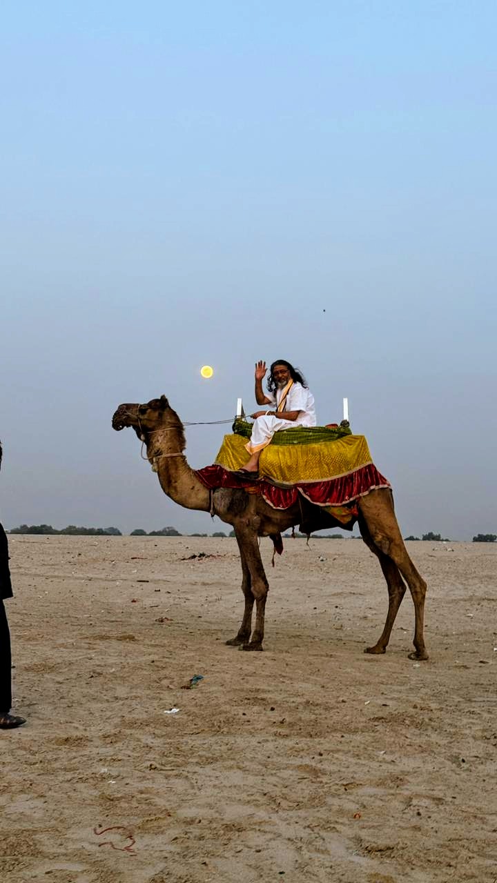 Guruji riding a decorated camel