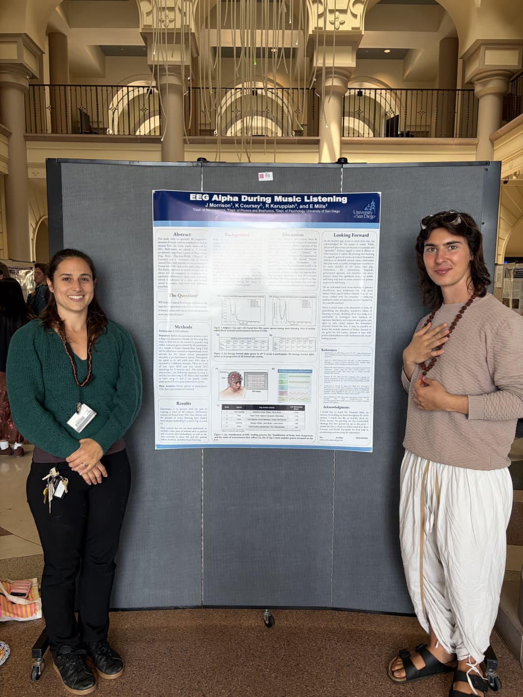 Jack Morrison and Dr. Elizabeth Mills beside their EEG research poster in a university atrium.